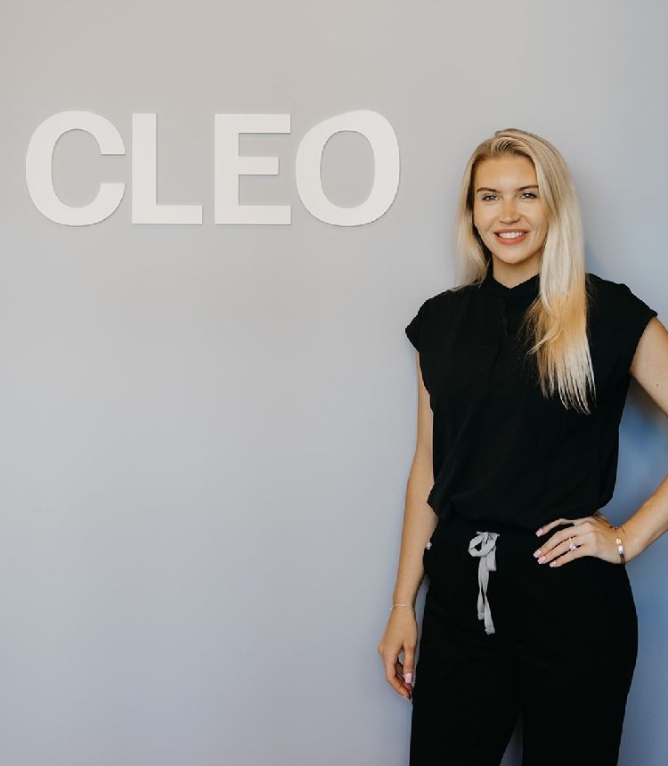 Woman in a black outfit standing against a gray background with 'CLEO' branding.