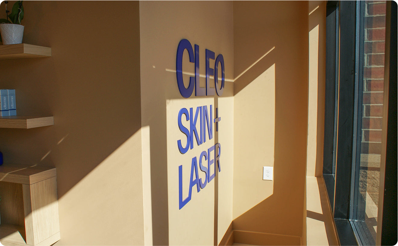 Cleo Skin Laser sign on a beige wall with shelves and a plant in the background.