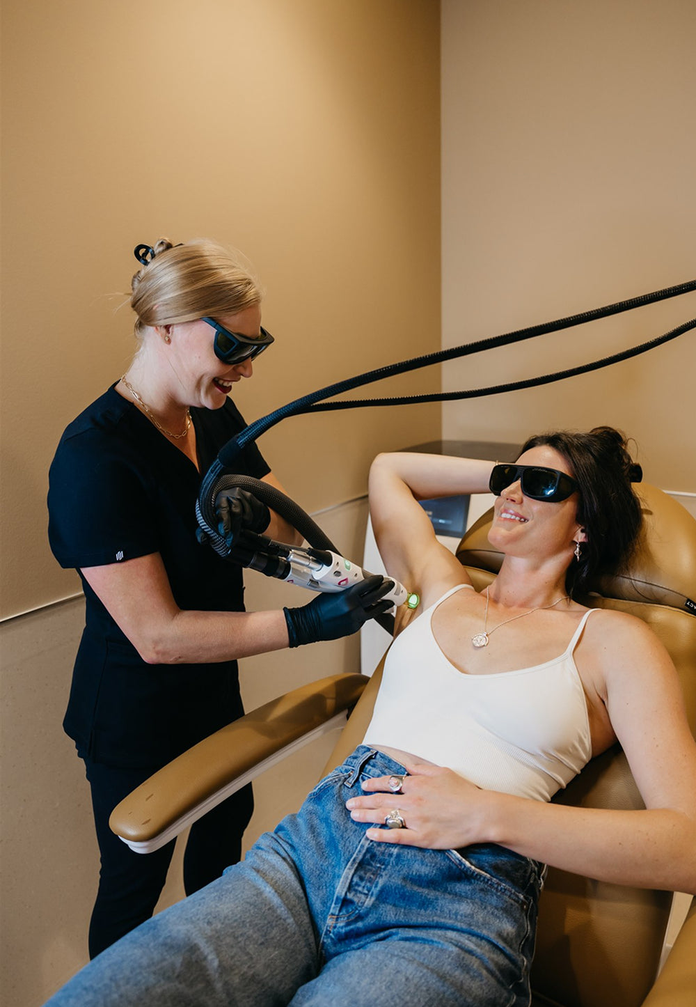 Woman receiving laser hair removal treatment from a professional in a clinical setting.