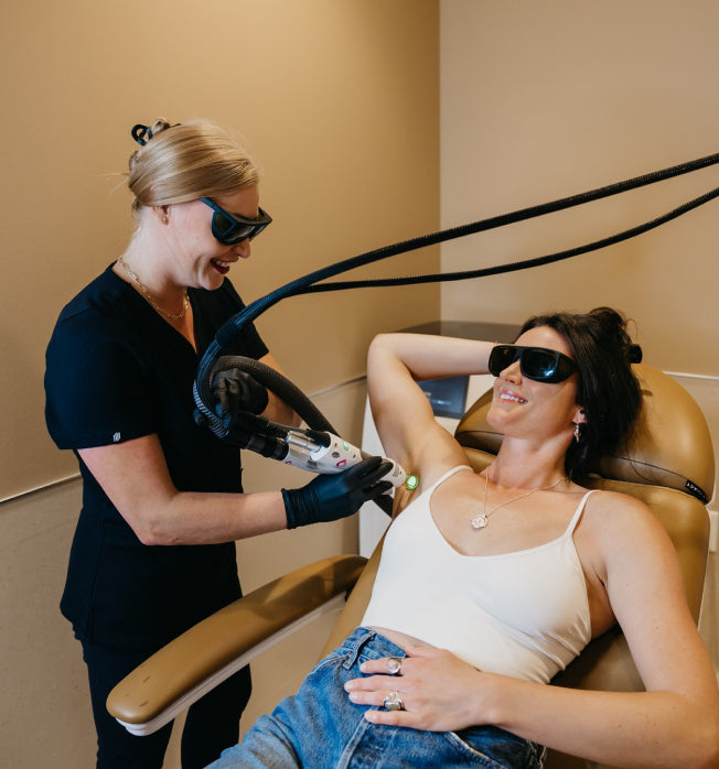 Woman receiving laser hair removal treatment from a professional in a clinical setting.