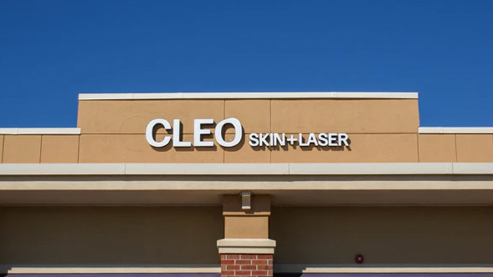 Cleo Skin + Laser clinic sign on a building with a clear blue sky.