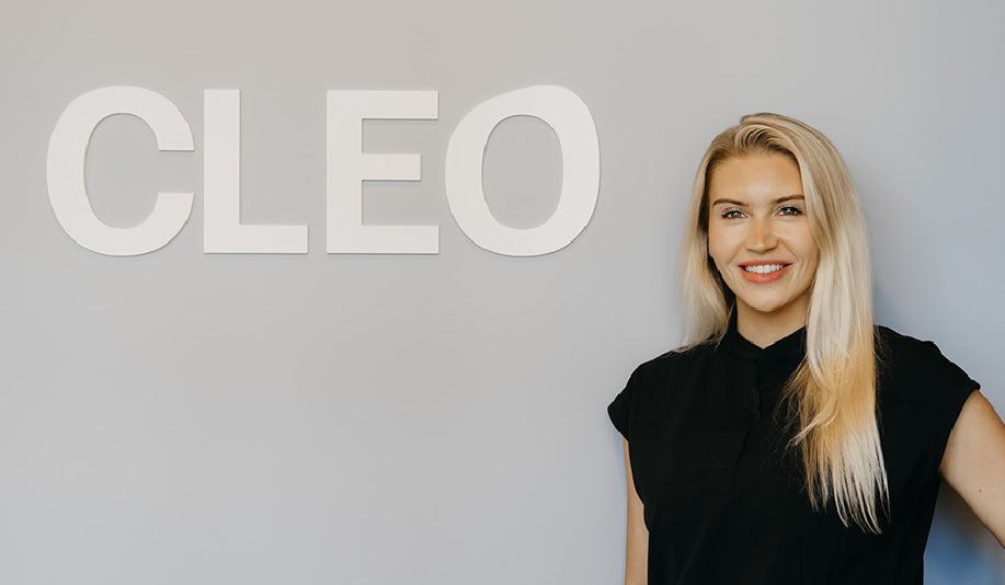 Smiling woman standing in front of Cleo brand name on wall